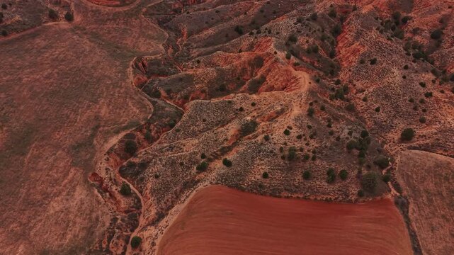 Aerial view of a canyon area showing steep slopes and patches of dry land. The scene captures the texture of the earth and the natural details of the landscape as day turns to night.
