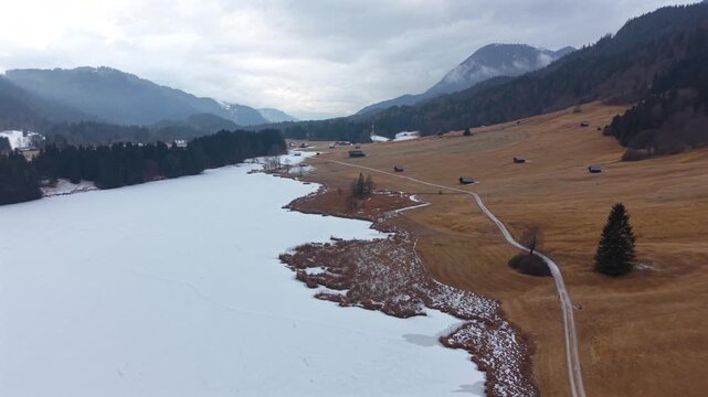 Cinematic drone shot of frozen Geroldsee in Kruen Germany. Wagenbruchsee is a premier winter tourism location. Snow-covered peaks and alpine serenity in Upper Bavaria.