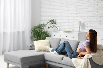 Obraz premium Pretty young woman resting on comfortable sofa in living room