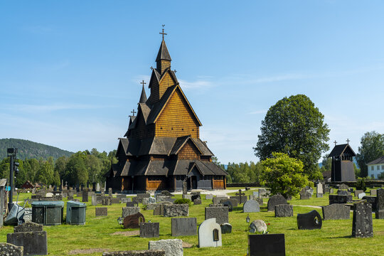 View of the Heddal Stave Church, a majestic wooden structure, rises above the ancient graveyard under a clear blue sky, Heddal, Telemark, Norway.
