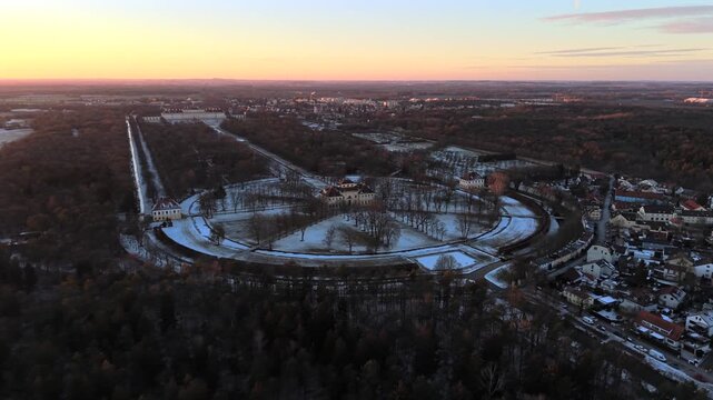 Cinematic aerial view of Palace Complex, Oberschleissheim, Bavaria, Germany. Drone footage shows snow covered baroque gardens, Neues Schloss and Lustheim Palace during winter sunset.