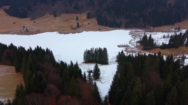 Stunning aerial of snowy Geroldsee Wagenbruchsee in Kruen Bavaria. A famous winter travel spot in the German Alps. Tranquil nature footage of a popular mountain lake.