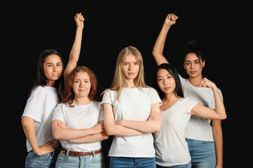 Obraz premium Beautiful young women with clenched fists showing muscles on black background. Women history month
