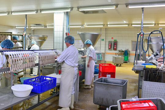 Production of sausages on a conveyor belt in a large meat processing plant - Industrial food processing - Workers in work clothes