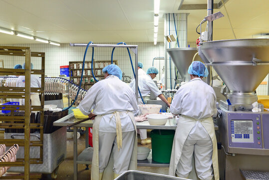 Production of sausages on a conveyor belt in a large meat processing plant - Industrial food processing - Workers in work clothes