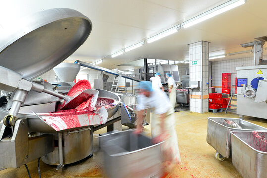 Production of sausages on a conveyor belt in a large meat processing plant - Industrial food processing - Workers in work clothes