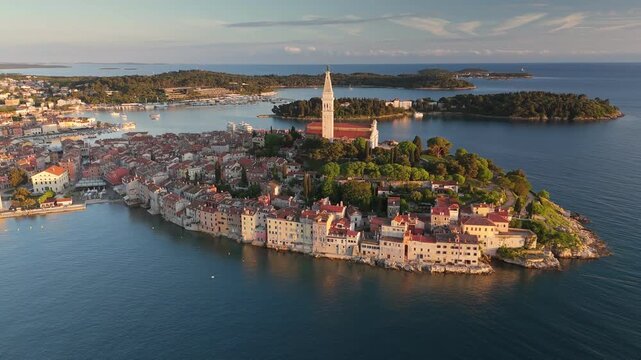 Aerial view of Rovinj old town at sunset, the historic St Euphemia's Church stands on the hill. Beautiful coastal cityscape of Istria is surrounded by blue Adriatic water. Rovinj at sunset, Croatia