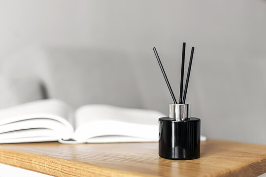 Minimalist reed diffuser on wooden shelf with open book, modern home decor concept.