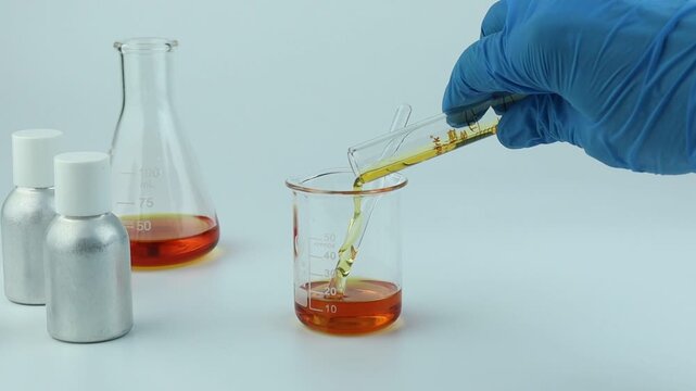 chemical science test tube , beaker or flask used on white table with blotting paper fragrance bottle and essential oil bottle used to blend nice scent for making perfume and candle by perfumer in lab