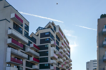 Modern apartment buildings with balconies under a clear blue sky. Contemporary residential architecture in an urban environment with geometric forms and clean design © Maciej Bonk