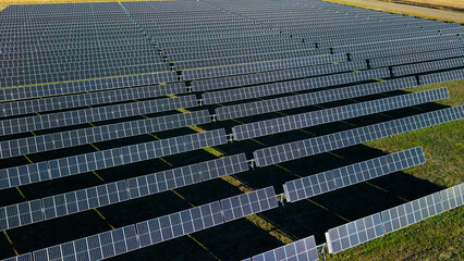 Fototapeta premium Aerial drone close view of solar power plant with long rows of photovoltaic panels generating renewable energy