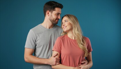 Fototapeta premium Young couple looking at each other with affection. Romantic man and woman standing together against blue background. Relationship and love concept