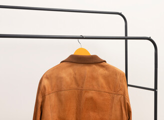 Brown leather jacket hanging on clothing rack. Outerwear garment suspended from hanger. Menswear wardrobe option for autumn spring outfit.. © valiantsin