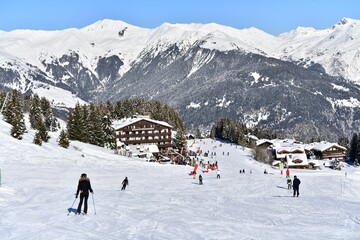 View of Courchevel ski resort by winter with skiers on the slopes and chalets in the background, French alps, France on 01/11/2024