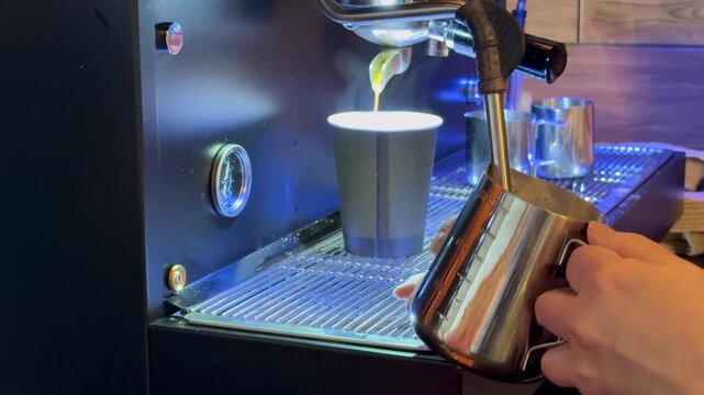 Barista preparing milk in a coffee machine for adding to coffee. Female hands are making coffee using professional metal machine in cafe. Barista is heating milk, whipping foam with frother, steam. 