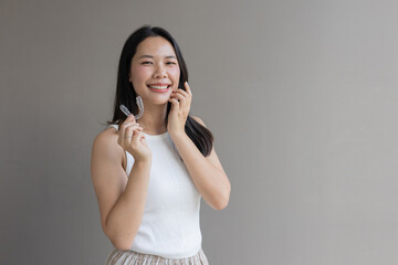 close up young asian beautiful woman smiling with hand holding dental aligner retainer (invisible) at dental clinic for beautiful teeth treatment course concept