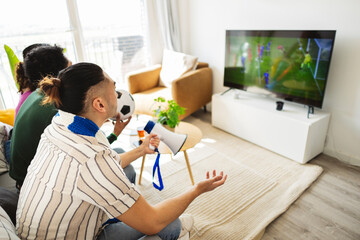 Diverse friends watching football game together cheering
