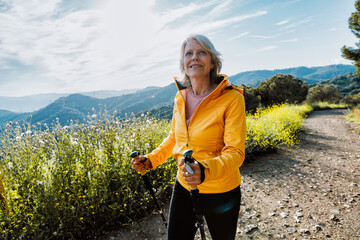 Active senior woman hiking on outdoor trail using trekking poles © oneinchpunch
