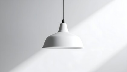 A simple white pendant lamp hangs from a black cord against a plain grey wall with light