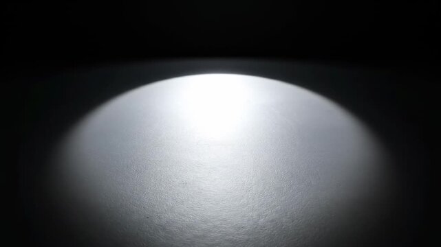 Spotlight shadow circle. Hard top-down light creating strong circular shadow falloff for dramatic visual emphasis