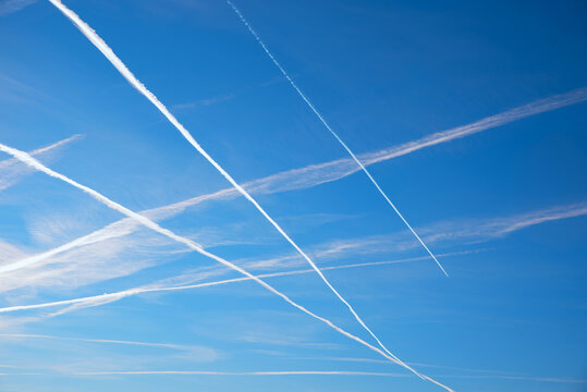 Blue sky crisscrossed with white contrails from airplanes. Heavy air traffic on holidays.