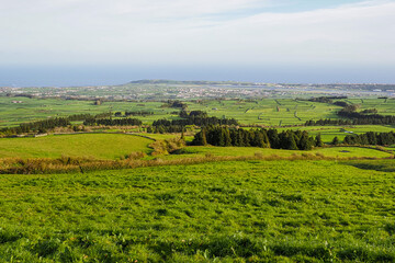 Obraz premium Coast of Terceira Island, Azores, Portugal. Cloudy day and beautiful rural landscape, green Achada Plain valley, Serra do Cume. Agricultural fields and pastures.