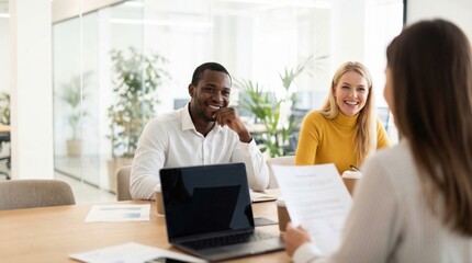 Obraz premium Happy professional team conducting friendly job interview in bright modern office, two smiling interviewers listening attentively while candidate presents resume