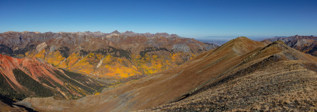 This colorful autumn San Juan Mountain panorama south of Ouray, Colorado, features golden aspen trees decorating the valley below.