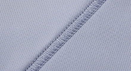 A close-up view of a light gray fabric with a visible seam
