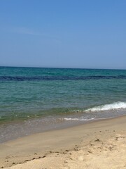 Clear blue ocean waves on sandy beach under blue sky
