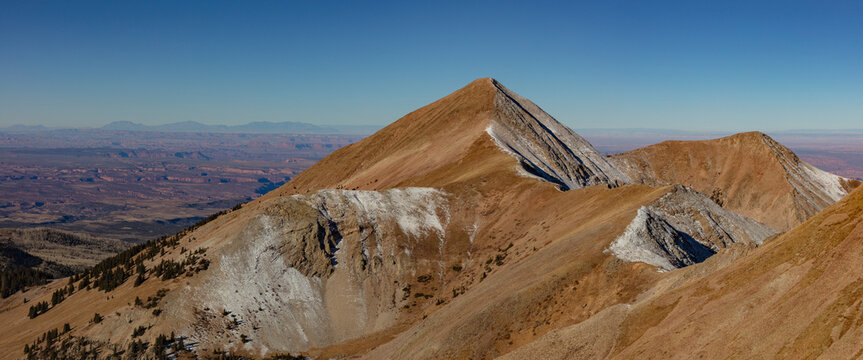 This scenic autumn La Sal Mountain panorama near Moab, Utah, features Mount Tukuhnikivatz (Mt Tuk) with the rugged red topography of Canyonlands National Park below.
