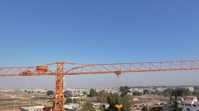 Vuelo frontal de drone desde gr&uacute;a torre hacia horizonte industrial al atardecer