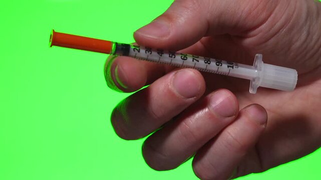 Diabetes treatment.
A person with diabetes holds an insulin syringe in his hand against an isolated background.