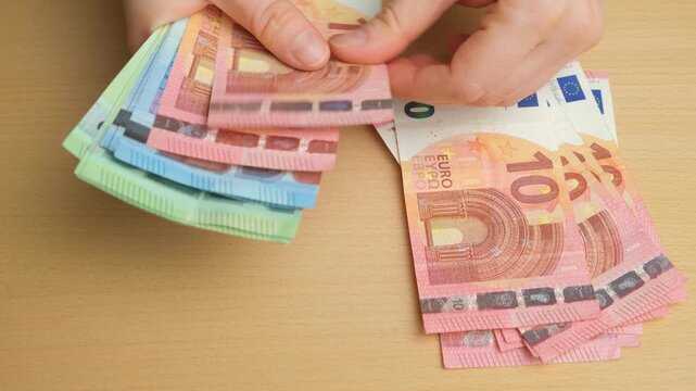 Counting a stack of euro banknotes on the table.