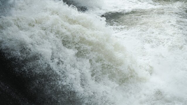 Close-up of rushing white water foam and turbulent river bubbles.