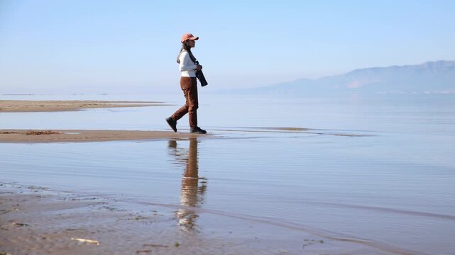 36-year-old female photographer strolling along the coastline during a bright sunny day in Delta Ebro, Tarragona, Spain.