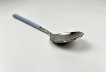 High Angle View of Stainless Steel Spoon with Light Blue Handle on White Background, Minimalist Kitchen Utensil and Cutlery, Single Tablespoon for Food and Dining Concept