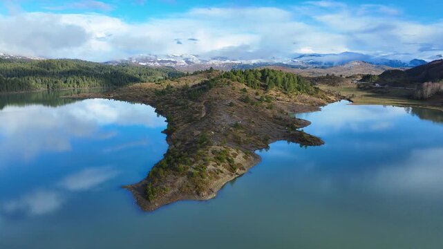 Aerial drone cinematic video of amazing artificial lake Aoou with beautiful nature and reflecting clouds near picturesque village of Metsovo surrounded by mountains of Pindus, Epirus, Greece