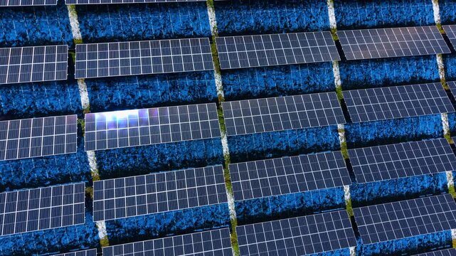 Close up aerial pattern of solar panels with snow. Overhead view of photovoltaic modules with patches of snow on the ground between rows.