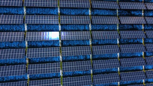 Abstract pattern of solar panels at power station. Top down aerial perspective creating a repetitive blue pattern of photovoltaic modules.
