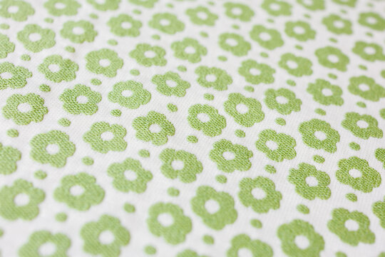 White fabric with green floral pattern macro background