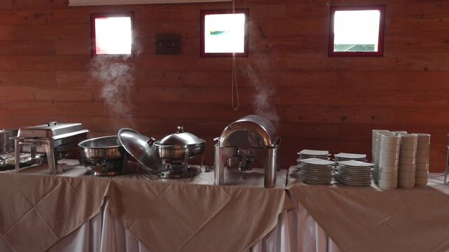 Self-service breakfast buffet with hot steam rising from stainless steel chafing dishes on a wooden background restaurant 3