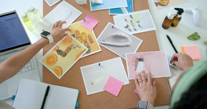 Hands are arranging prints and pink notes on corkboard at desk after review to finalize layout