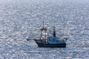 Fototapeta premium Fishing trawler sailing on glimmering open sea