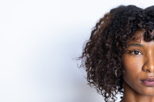 Adult female posing with curly hair and hoop earring in studio on right side, copy space