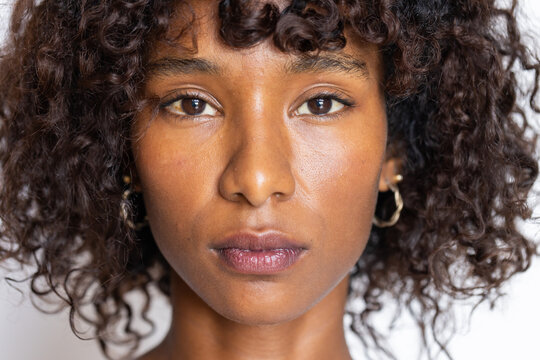 African American woman holding steady gaze toward camera in studio, showing gold hoop earrings