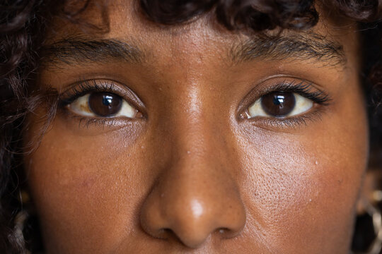 African American woman focusing on eyes nose with curly hair and gold hoop in studio close-up