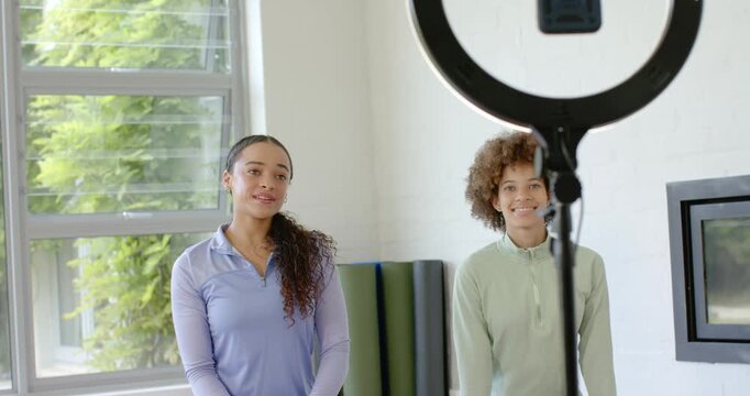 African American female hosts in sportswear greeting studio by ring light left waving for wellness