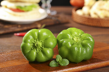 Fresh Green Bell Peppers on Wooden Cutting Board with Mint Leaves in Kitchen © DangThi