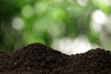 Fertile soil mounds with green bokeh background for environmental protection and sustainable growth © DangThi
